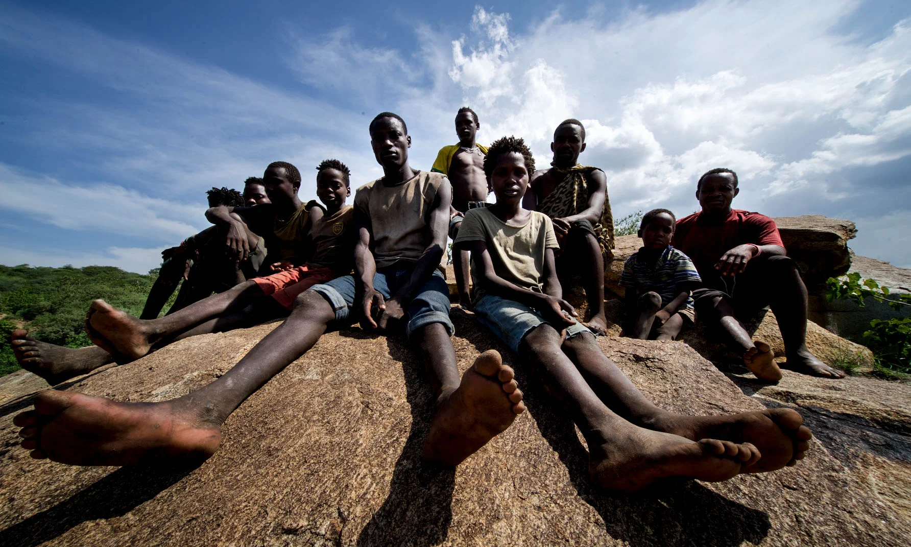 Hadza community members sitting on a rock under a wide sky