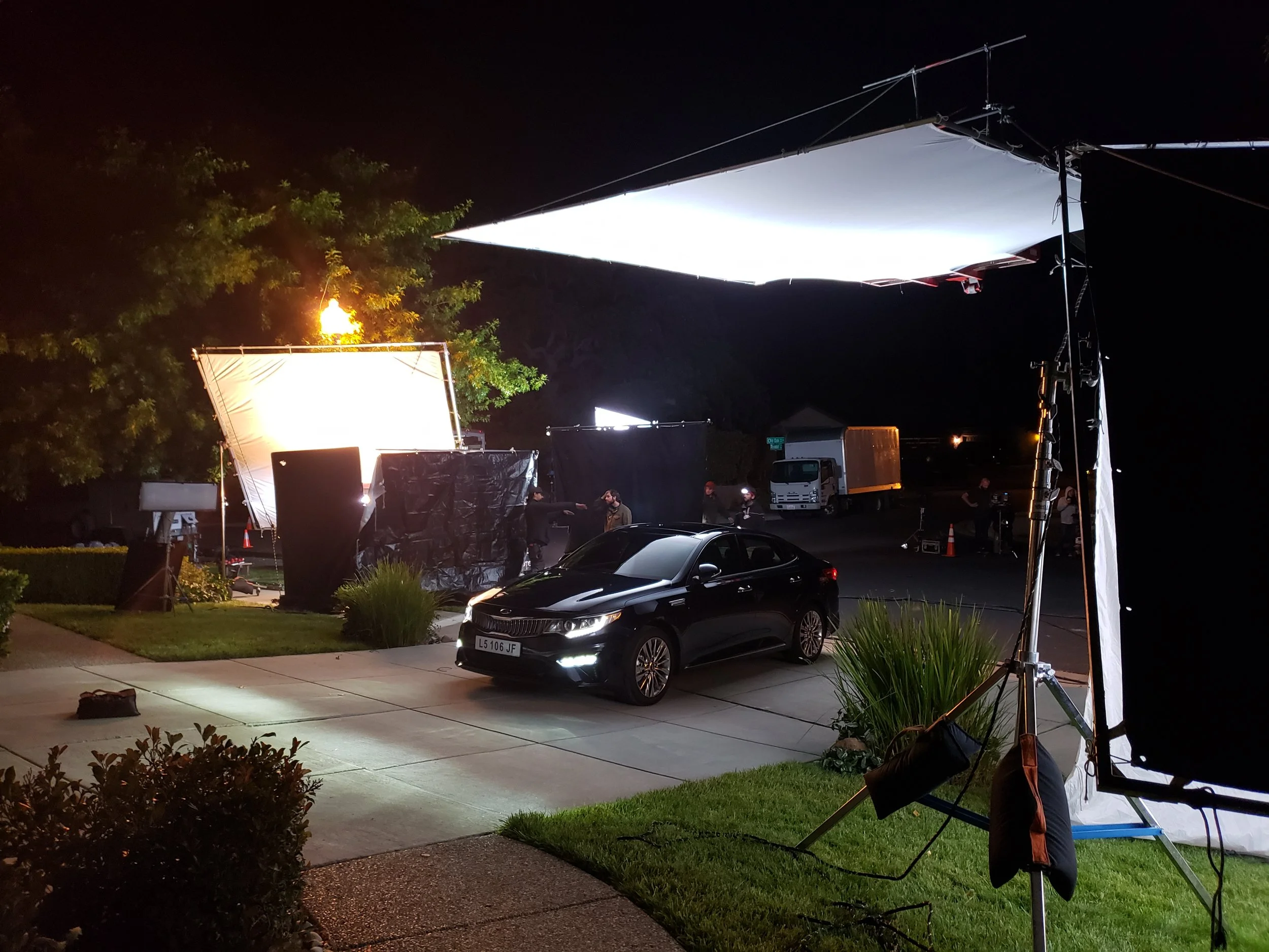 Night exterior set with a Kia sedan under large film lighting
