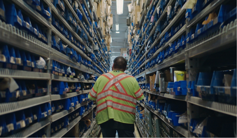 A worker walking a warehouse aisle, from a Unicorn Studios production